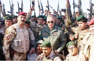  ??  ?? Iraqi Defense Minister Khalid Al-Obeidi, center, surrounded by soldiers, at the Iraqi Army headquarte­rs in Samarra, 95 km north of Baghdad. (AP)