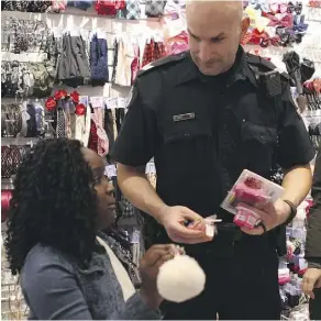  ?? CLAIRE THEOBALD ?? Sgt. Dan Tames helps Gracious Blamo, 9, pick out items at Londonderr­y Mall during the CopShop event, where 26 students are paired with police officers for a Christmas shopping spree.