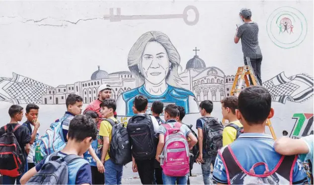  ?? Agence France-presse ?? ↑
School children watch as Palestinia­n artists paint a mural honouring Shireen Abu Akleh in Khan Younis, Gaza Strip, on Saturday.