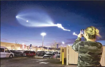  ??  ?? Using her smartphone, a hair salon employee takes a shot of the light display of SpaceX’s Falcon 9 rocket launch in Apple Valley, California on Friday night.