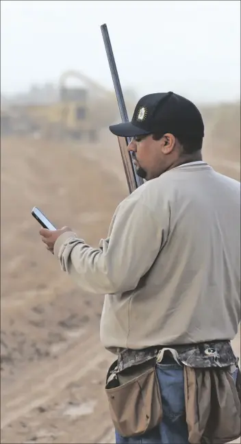  ??  ?? YUMA’S ALFONSO ZAVALA takes a break from scanning the sky for doves to take a phone call on the morning of opening day.