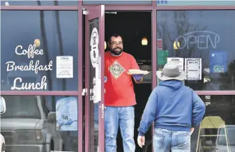  ?? Jerilee Bennett / Associated Press ?? Jesse Arellano hands a burrito to a customer at his restaurant in Castle Rock, Colo. His license was suspended indefinite­ly for opening in defiance of rules banning inperson dining.