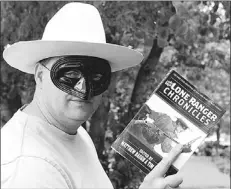  ?? — Photo by The Canadian Press ?? Tim Lasuita of Red Deer, Alta. holds up a copy of “The Lone Ranger Chronicles” in Red Deer, Alta., June 15.