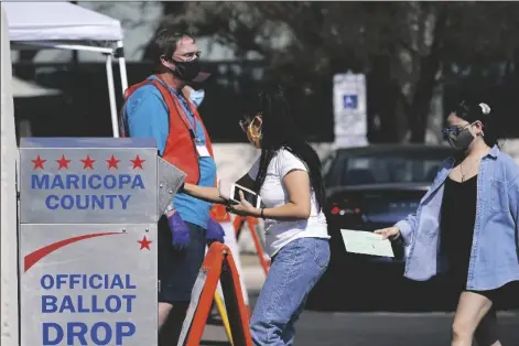  ?? ROSS D. FRANKLIN/ASSOCIATED PRESS ?? VOTERS DROP OFF BALLOTS AS VOLUNTEERS look on at the Maricopa County Recorder’s Office on Oct. 20, 2020, in Phoenix.