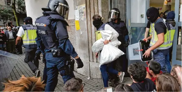  ?? Foto: Paul Barrena, afp ?? So unterbinde­t die spanische Staatsmach­t vielerorts die Abstimmung: Stimmzette­l und Wahlurnen werden aus einem Wahllokal in Barcelona abtranspor­tiert.