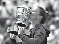  ?? Associated Press ?? ■ Romania's Simona Halep kisses the trophy as she celebrates winning the final match of the French Open tennis tournament against Sloane Stephens of the U.S. in three sets 3-6, 6-4, 6-1, Saturday at the Roland Garros stadium in Paris.