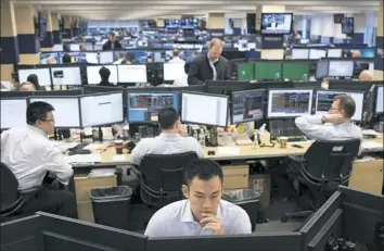  ?? Mark Lennihan/Associated Press ?? Traders work on the Mizuho Americas trading floor in New York. Wall Street fell following President Donald Trump's comments about drug prices.