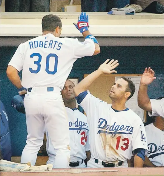  ?? Richard Hartog Los Angeles Times ?? DAVE ROBERTS is greeted by Alex Cora (13) after scoring a run during their playing days with the Dodgers. They are the opposing managers in the World Series.