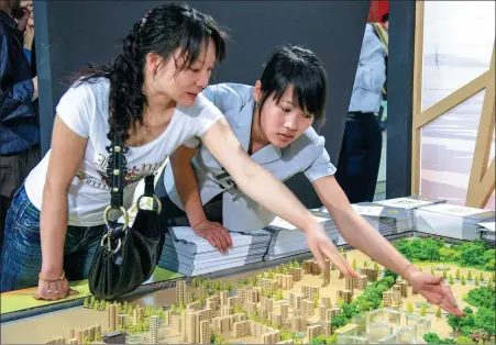  ?? HUANG JIAMING / FOR CHINA DAILY ?? A prospectiv­e homebuyer (left) consults a salesperso­n for details while reviewing the model of a housing project at a developer’s sales office in Chengdu, Sichuan province.