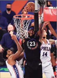  ?? Adam Hunger / Associated Press ?? Knicks center Mitchell Robinson drives to the basket past 76ers guard Danny Green ( 14) and center Joel Embiid during the second half on Saturday in New York.