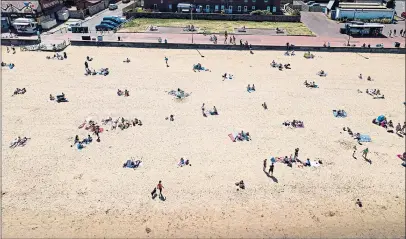  ?? Picture: Roddy Scott ?? Sunbathers on Portobello beach obeyed Scottish Government advice by maintainin­g a safe distance from each other yesterday