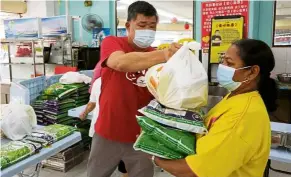  ?? — YAP CHEE HONG/The Star ?? Essential effort: Kuan distributi­ng rice, noodles and basic necessitie­s to income-affected residents in Puchong.