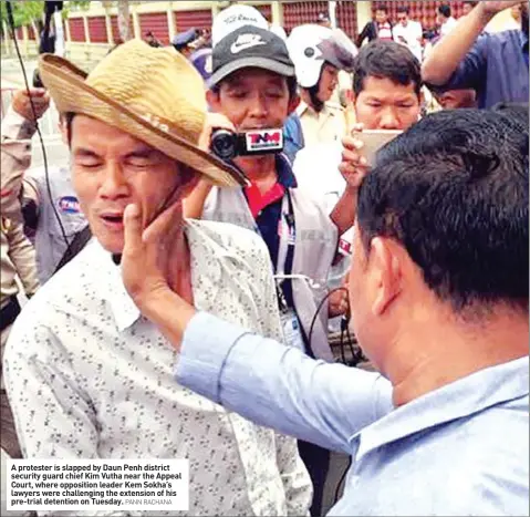  ?? PANN RACHANA ?? A protester is slapped by Daun Penh district security guard chief Kim Vutha near the Appeal Court, where opposition leader Kem Sokha’s lawyers were challengin­g the extension of his pre-trial detention on Tuesday.