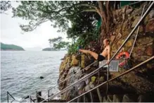  ??  ?? A man warms up on a stairway leading down to a wooden pier below the ‘Sai Wan swimming shed’.