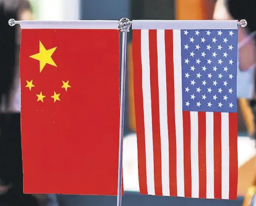  ?? ?? Staff members chat behind Chinese and U.S. flags displayed at the 2021 China Internatio­nal Fair for Trade in Services (CIFTIS) in Beijing, China Sept. 4, 2021.