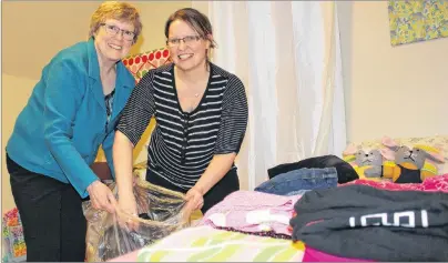  ?? MILLICENT MCKAY/JOURNAL PIONEER ?? Carolyn Francis, left, and April Ramsay, members of the Kensington and Area Refugee Sponsorshi­p Initiative, go through a bag of donated girls clothes, sorting through sizes for a member of the Syrian refugee family who is moving to Kensington.