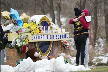  ?? PHOTOS BY PAUL SANCYA — THE ASSOCIATED PRESS ?? Students hug at a memorial at Oxford High School in Oxford on Wednesday. Authoritie­s say a 15-year-old sophomore, Ethan Crumbley, opened fire at Oxford High School, killing three students and wounding seven other people on Tuesday. A fourth student died Wednesday morning from his wounds.