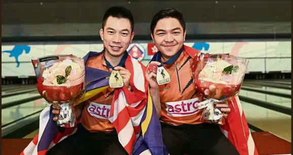  ??  ?? It’s raining gold!: Adrian Ang (left) and Tun Hakim Tun Hasnul Azam with their gold medals at the South China Athletics Associatio­n Bowling Centre yesterday.