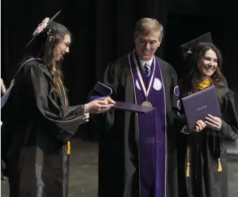  ??  ?? LIKE MOTHER LIKE DAUGHTER: Curry College President Kenneth Quigley, center, presents diplomas to Hannah Lawrence, left, and her mother Luciana Lawrence, right, during the commenceme­nt ceremony.