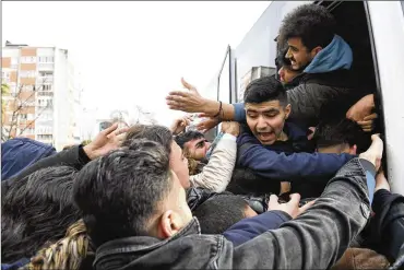  ?? ASSOCIATED PRESS ?? Migrants struggle to board a bus to the Greek border Friday. NATO envoys held emergency talks following the killing of 33 Turkish soldiers in northeast Syria, as scores of migrants gathered to seek entry into Europe.