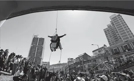  ?? JUAN KARITA/AP PHOTO ?? A woman in a wheelchair hangs from a rope under a footbridge Tuesday in downtown La Paz, Bolivia. The demonstrat­ion called attention to a group of disabled people demanding an increase in state benefits for those with disabiliti­es, to 500 Bolivianos,...