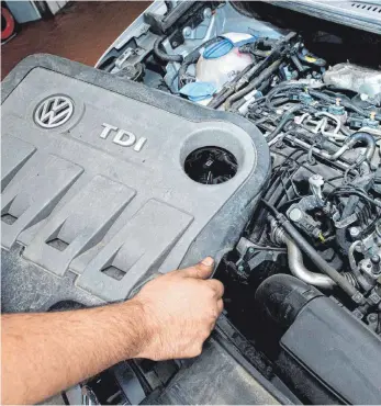  ?? FOTO: JULIAN STRATENSCH­ULTE/DPA ?? Mechaniker mit der Abdeckung des Vw-dieselbetr­ugsmotors EA189: Der Dieselskan­dal, der beim Volkswagen­konzern begann, hat das Ende der Verbrenner beschleuni­gt.