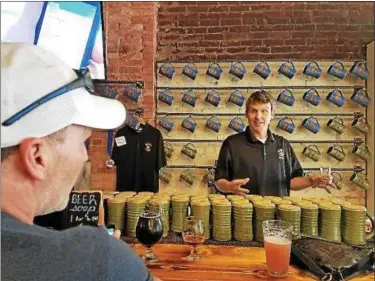  ?? PARIS WOLFE — THE NEWS-HERALD ?? Eric Latham, owner and head brewer at Johnson City Brewing, talks about how he accidental­ly dropped an entire bottle of coriander in a batch of beer. And the result — Kick of Coriander — is now a regular on tap.