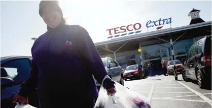  ??  ?? SUNBURY: This file photo taken on April 22, 2015 shows a woman as she carries her purchases in plasctic shopping bags outside a Tesco supermarke­t. — AFP
