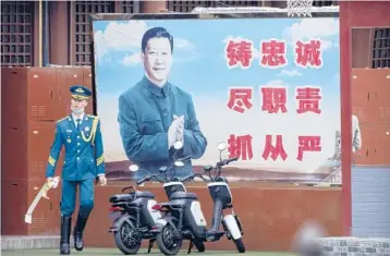  ?? MARK SCHIEFELBE­IN/AP ?? An honor guard member walks past a poster of Chinese leader Xi Jinping on Sept. 18 in Beijing.