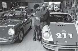  ??  ?? Magnus Walker embraces wife Karen in his warehouse.