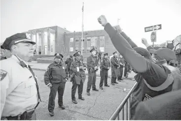  ?? Alex Brandon / Associated Press ?? Marchers raise their fists in front of Baltimore police guarding the department’s Western District station during a march for Freddie Gray. He died from spinal injuries about a week after he was arrested.