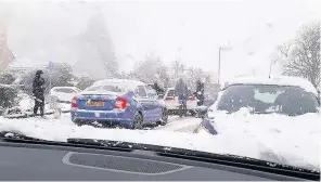  ??  ?? Disruption Parents drop off their children to Machanhill Primary School in Larkhall and help cars which got stuck in the snow