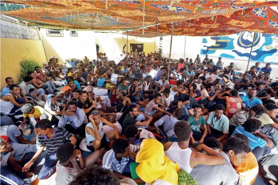  ??  ?? Des migrants attendent dans un centre d’accueil ouvert par les autorités libyennes, près de l’aéroport de Tripoli, en septembre 2018.