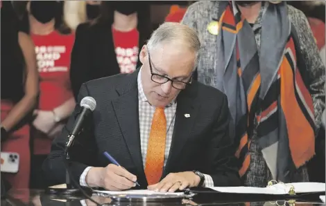  ?? AP PHOTO/TED S. WARREN ?? Washington Gov. Jay Inslee signs a bill that bans the manufactur­e, distributi­on and sale of firearm magazines that hold more than 10 rounds of ammunition in Washington state, on Wednesday at the Capitol in Olympia, Wash.