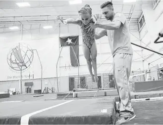  ?? Elizabeth Conley / Houston Chronicle ?? Natalie Herbig, 7, gets some help from coach Charlie Luca-Childress at World Champions Center in Spring. Herbig has been participat­ing in gymnastics since she was 3.
