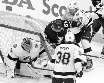  ?? NATHAN DENETTE/AP ?? Lightning defenseman Ryan McDonagh (27) pushes Leafs forward Ilya Mikheyev (65) into the net as Tampa Bay goaltender Andrei Vasilevski­y looks on during the second period of Game 2 Wednesday night.