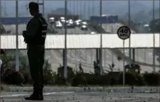  ?? Juan Barreto/AFP/Getty Images ?? A member of Venezuela's Bolivarian national guard patrols Monday at the Tienditas Internatio­nal Bridge in Urena, Tachira state, on the border with Colombia, back-dropped by containers placed by Venezuelan military forces to block the bridge.