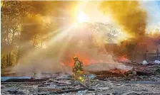  ?? IAN MUNRO /DAILY NEWS-RECORD VIA AP ?? A firefighte­r walks through the burning rubble of a shopping center Saturday after an explosion in Harrisonbu­rg, Va. Three people were transporte­d for injuries from the blast. The cause of the explosion has not been released yet.