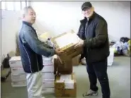  ?? JOSEPH ROGINSKI VIA AP ?? Joseph Roginski, right, holds a package in a storeroom of the Misawa City Hall in Japan, where donations of clothing and supplies were being kept for earthquake relief efforts. He says that while the cost of living is higher in Japan, access to health...