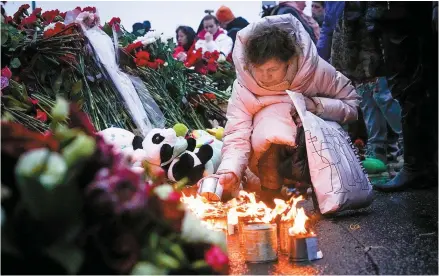  ?? AP-Yonhap ?? A woman lights candles at fence next to Crocus City Hall, on the western edge of Moscow, Russia, Saturday. Russia’s top state investigat­ive agency says the death toll in the Moscow concert hall attack has risen to at least 133.