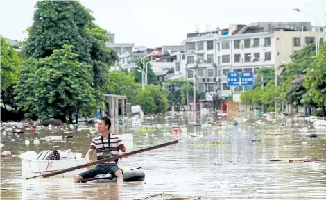  ?? HANDOUT/GETTY IMAGES ?? A man uses an improvised flotation device to move through floodwater­s on a flooded street in Liuzhou, Guangxi province, on Tuesday. Rainstorms have triggered floods across central and southern China, forcing hundreds of thousands of people from their...