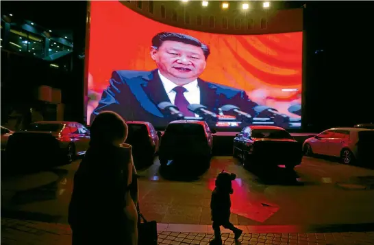  ?? AP ?? A child walks past a large screen showing Chinese President Xi Jinping near a car park in Kashgar, western China’s Xinjiang region.