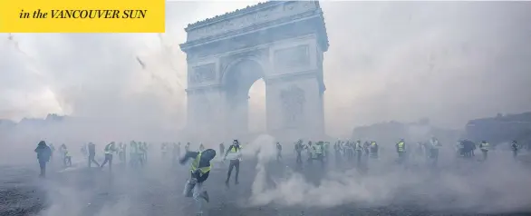  ?? VERONIQUE DE VIGUERIE / GETTY IMAGES ?? Tear gas surrounds “yellow vest” protesters as they clash with riot police Saturday near the Arc de Triomphe in Paris. Police said 133 people were injured and 412 arrested.