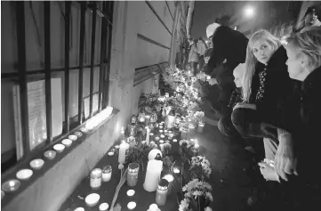  ??  ?? People light candles in front of a school building during a vigil for Hungarian students who were killed and injured during a bus accident in northern Italian city of Verona, in Budapest, Hungary. — Reuters photo