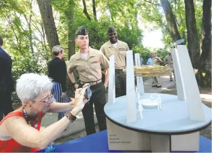  ?? STAFF PHOTO BY TIM BARBER ?? PattiAnn Smith takes an up-close photo of a model of the “Wreath of Honor” monument by Norman Lee on the site of the future Fallen Five Memorial at the Tennessee Riverpark on Thursday. Standing by are Marine Capt. Patrick Sansburg, center, and 1st Sgt. Christophe­r Myers, of Mike Battery.