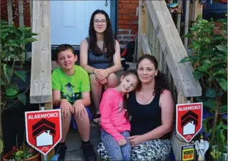  ?? KATHY RENWALD, SPECIAL TO THE HAMILTON SPECTATOR ?? Lisa Walker holds daughter Daisy, as daughter Alyssa and nephew Tyler perch behind her on the front stairs of their Barton Street house. The kids are all proud of the garden Walker made out of nothing in the tiny front yard.