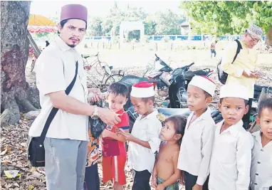  ??  ?? SUMBANGAN: Ustaz Ahmad Abdul Hamid memberi wang kepada para pelajar sekolah agama Kampung Prik Bui.