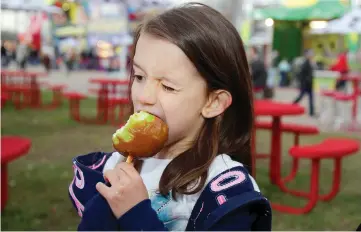  ??  ?? James Nielsen / Houston Chronicle Taylor Morrow of Fort Hood eats a caramel apple at the Houston Livestock Show and Rodeo.