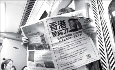  ?? Photo: Cui Meng/GT ?? An MTR passenger reads a newspaper with a back page petition headlined “Enough for Hong Kong”on Thursday. The petition is published by local residents on local newspapers to voice opposition against growingly violent and rampant rioting mobs in the city.