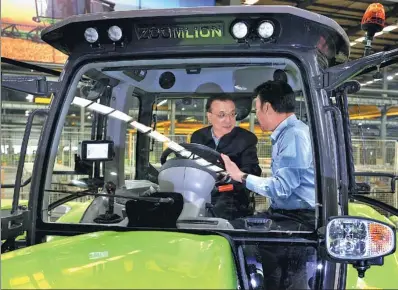  ?? WU ZHIYI / CHINA DAILY ?? Premier Li Keqiang receives an introducti­on to the Zoomlion 230-horsepower tractor from the company’s deputy director, Wang Jinfu, in Kaifeng, Henan province, on Monday. China previously depended on overseas technology for such products.